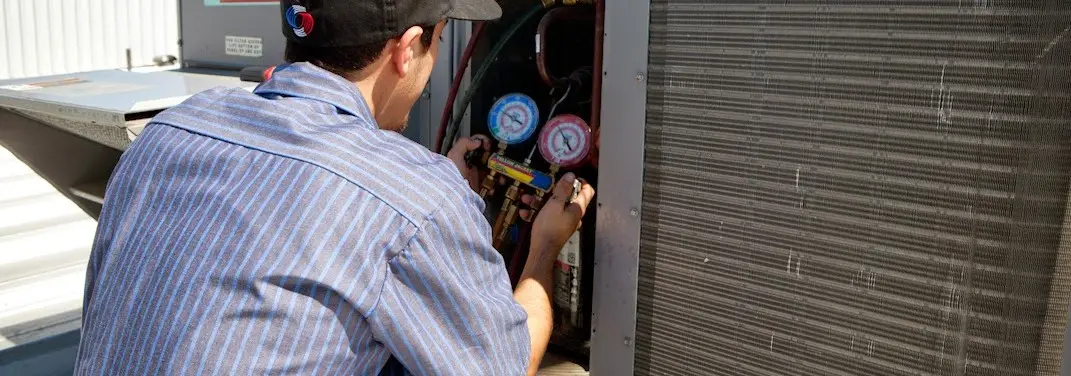 HVAC technician servicing a condenser unit in Groveton
